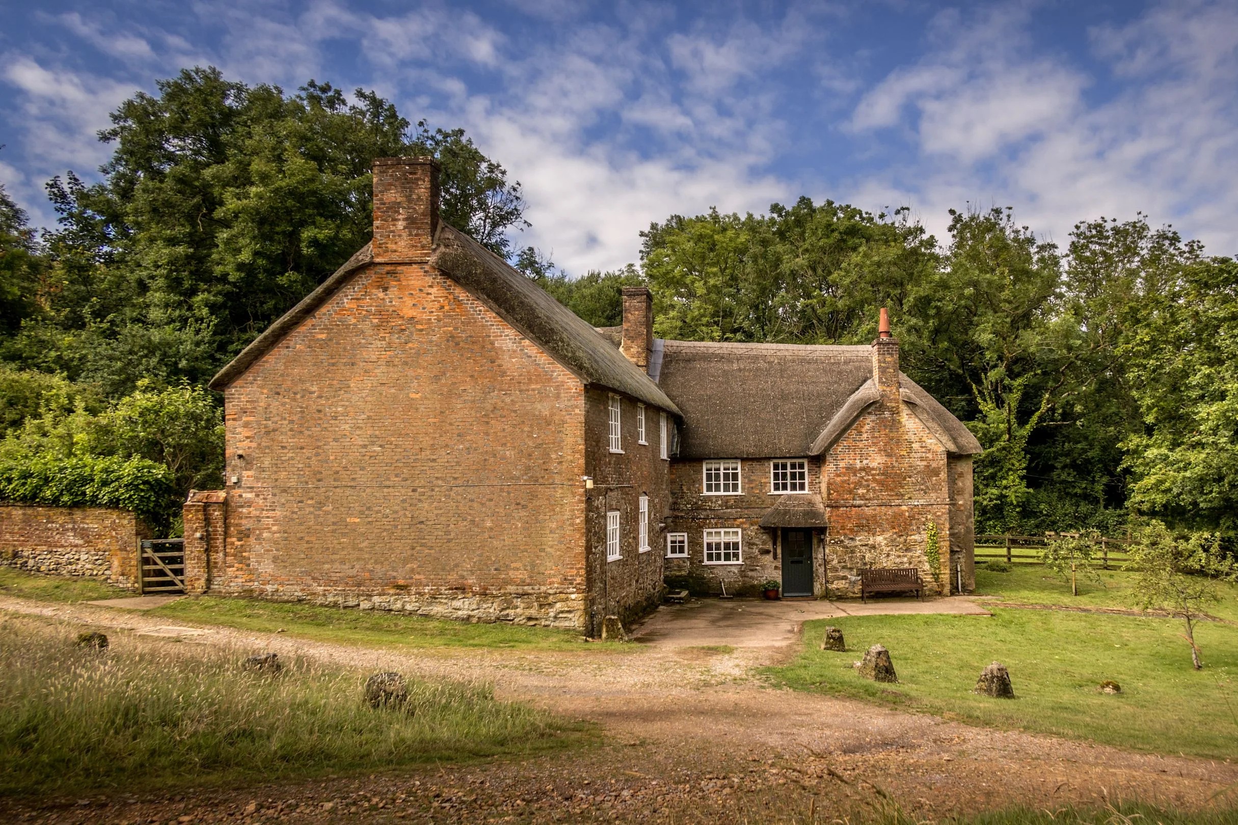 Brick farmhouse surrounded by trees at Ash Cottage, Bridport, Dorset